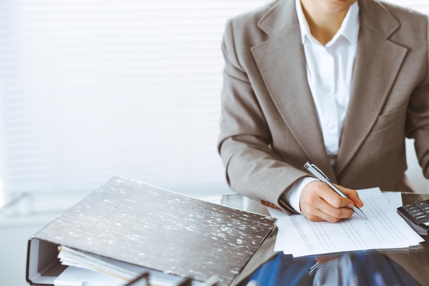 Mujer tenedora de libros o inspectora financiera haciendo informes, calculando o comprobando el saldo, primer plano. Conceptos de negocio, auditoría o impuestos.