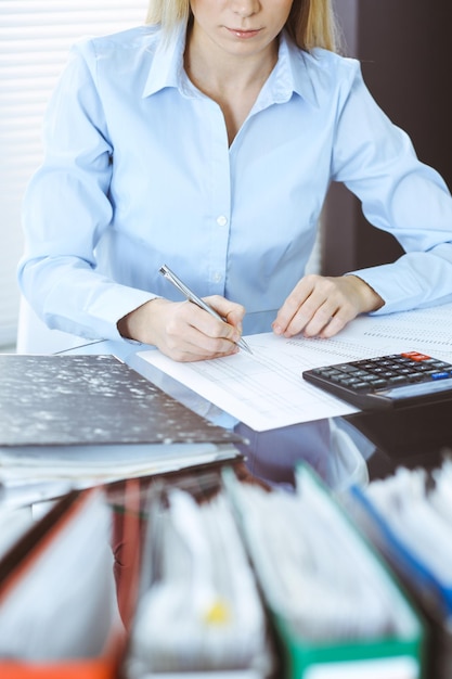 Foto mujer tenedora de libros o inspectora financiera haciendo informes, calculando o comprobando el saldo, primer plano. conceptos de negocio, auditoría o impuestos.