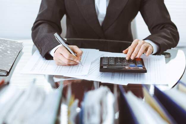 Mujer tenedora de libros o inspectora financiera haciendo informes, calculando o comprobando el saldo, primer plano. Conceptos de negocio, auditoría o impuestos.