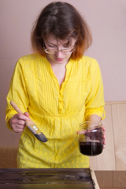 Foto una mujer teñida en un tablero de madera oscura. trabajo creativo en el taller. hecho a mano en madera