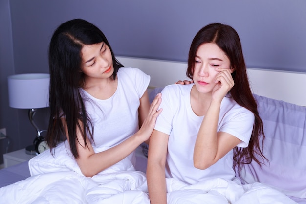 mujer teniendo problema y la mujer la anima en la cama