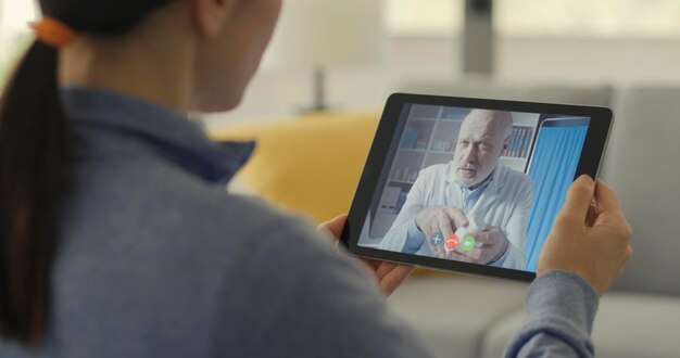 Foto mujer teniendo una videochat con su médico usando una tableta digital