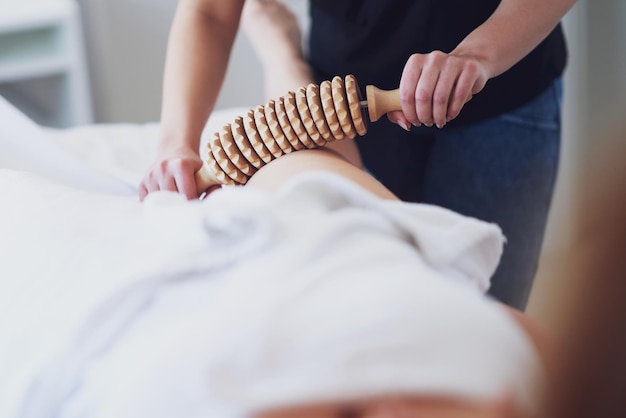 Mujer en terapia de masaje con herramientas de madera.