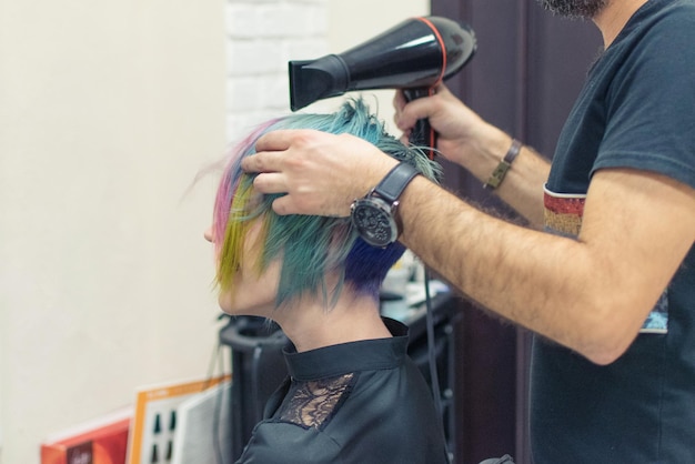 Una mujer termina de teñirse la cabeza de azul en la peluquería Cambia la imagen de una mujer