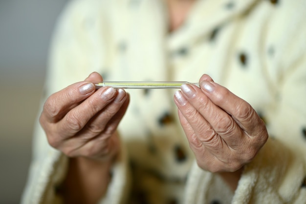 Mujer, con, termómetro, en, ella, primer plano de la mano