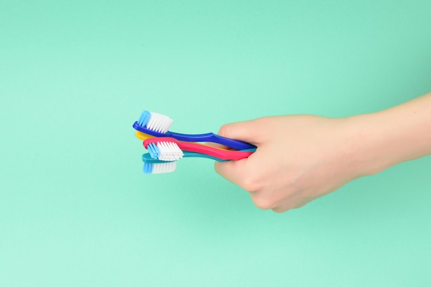 La mujer tiene cepillos de dientes en la mano sobre un fondo verde.