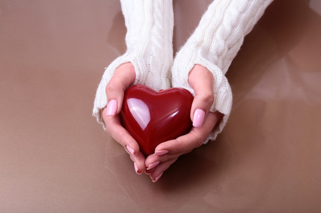 Foto una mujer tiene un corazón rojo en sus manos.