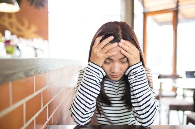 La mujer tiene dolor de cabeza en el café