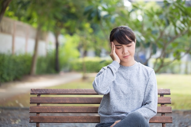 La mujer tiene dolor de cabeza en el parque