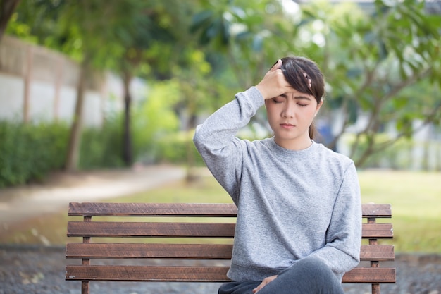 La mujer tiene dolor de cabeza en el parque