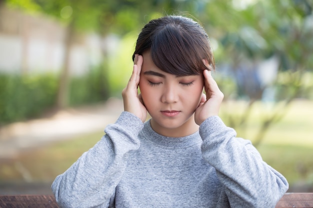 La mujer tiene dolor de cabeza en el parque