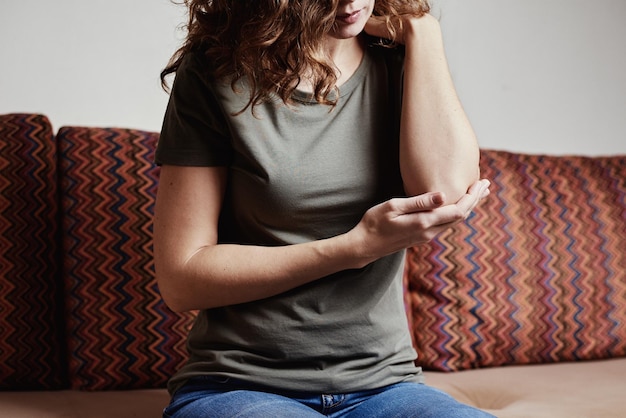 La mujer tiene dolor en el codo tocando la mano