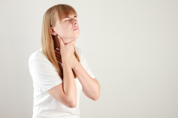 La mujer tiene dolor de garganta en un fondo blanco