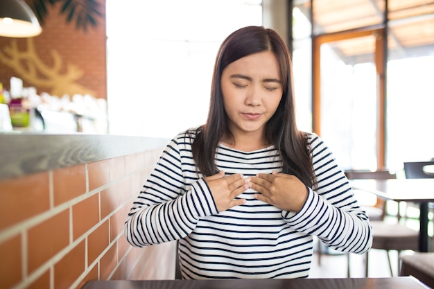 La mujer tiene dolor de pecho en el café