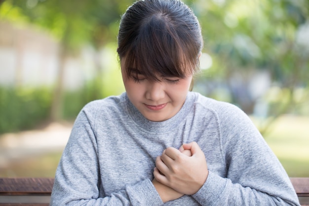 La mujer tiene dolor de pecho en el parque