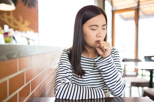 La mujer tiene estornudos en el café