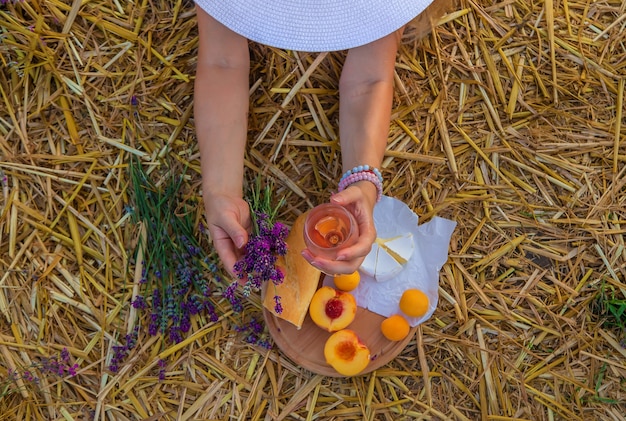 Una mujer tiene vino en vasos. Picnic en el campo de lavanda. Enfoque selectivo.