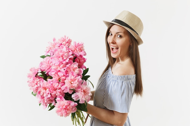 Mujer tierna joven en vestido azul, sombrero con ramo de hermosas flores de peonías rosas aisladas sobre fondo blanco. Día de San Valentín, concepto de vacaciones del Día Internacional de la Mujer. Área de publicidad.