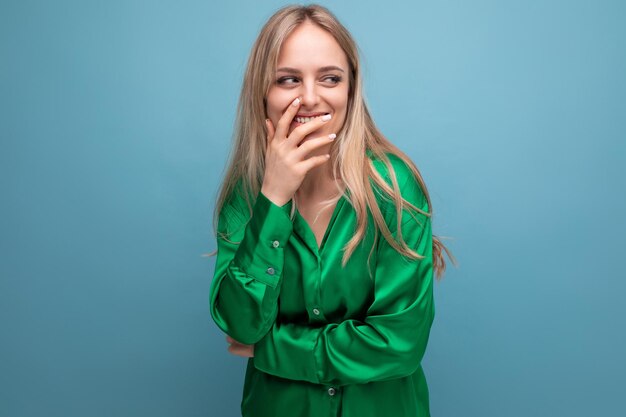 Mujer tímida con camisa verde mirando hacia otro lado tímidamente en el fondo azul del estudio