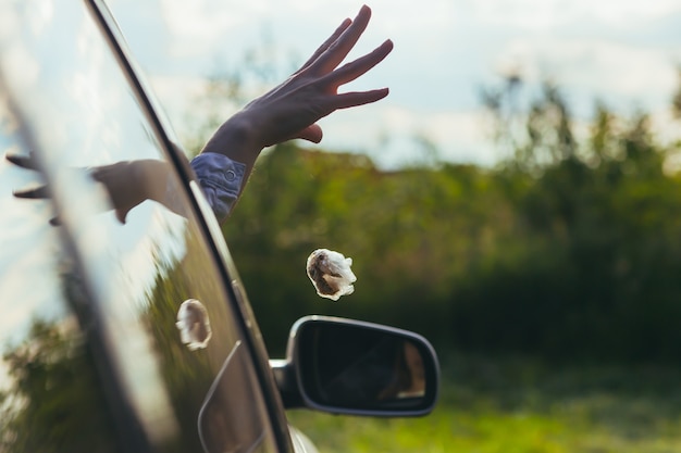 Foto mujer tira basura por la ventanilla del coche