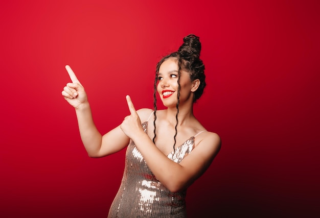 La mujer tira de su dedo índice hacia un lado sobre un fondo rojo apuntando a algo al costado de un espacio de copia vacío que anuncia el concepto publicitario del producto