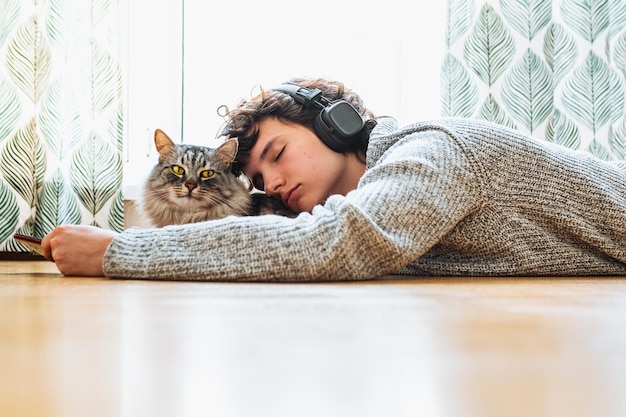 Una mujer tirada en el suelo con un gato en la cabeza.