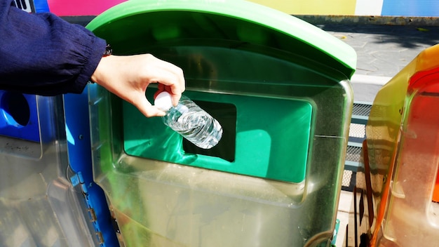 Mujer tirando botellas de agua a un basurero