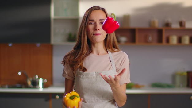 Mujer tirando pimientos en la cocina Ama de casa mirando a la cámara en casa