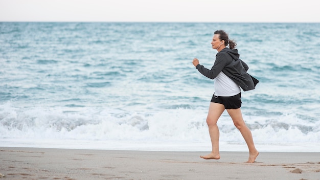 Foto mujer de tiro completo corriendo en la playa