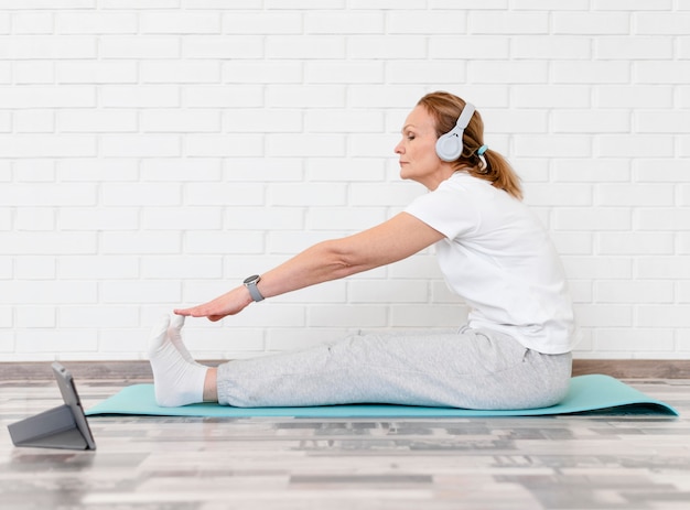 Mujer de tiro completo estirando sobre estera de yoga