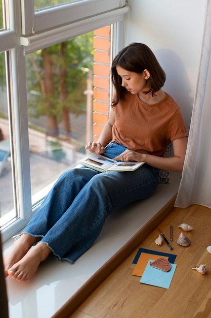 Mujer de tiro completo haciendo un diario creativo