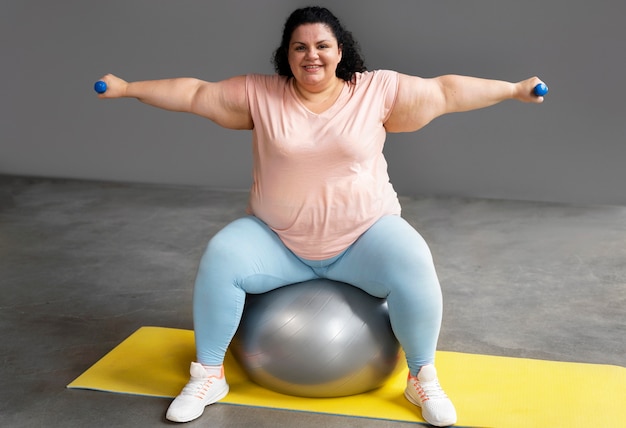 Foto mujer de tiro completo haciendo ejercicio en el gimnasio