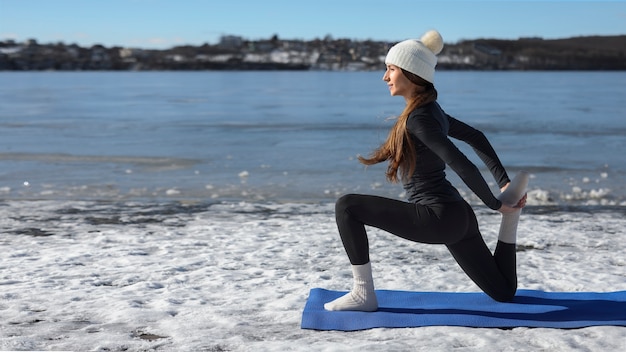 Mujer de tiro completo haciendo yoga clima invernal