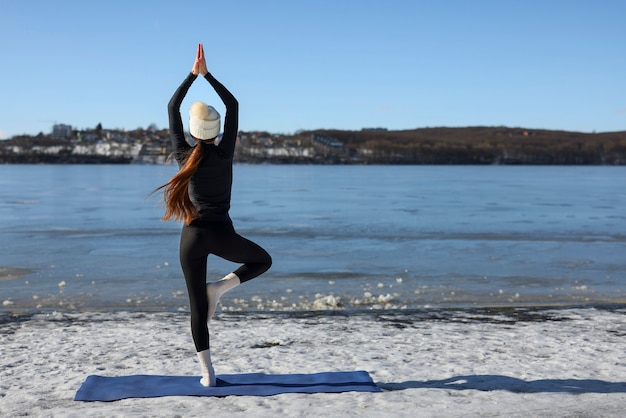 Mujer de tiro completo haciendo yoga clima invernal