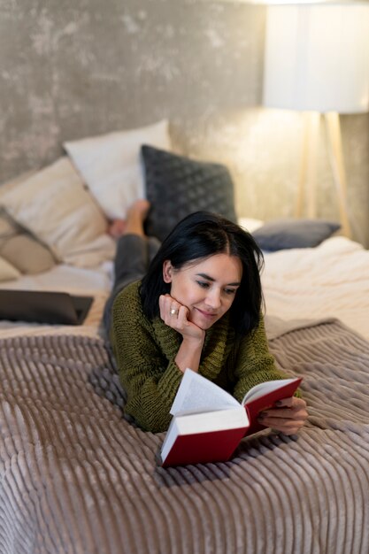 Foto mujer de tiro completo leyendo en la cama