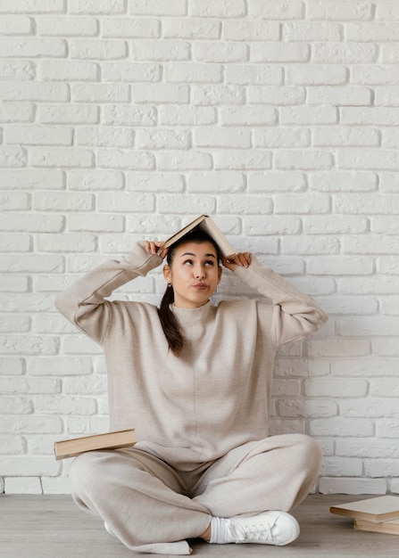 Foto mujer de tiro completo con libro en la cabeza.