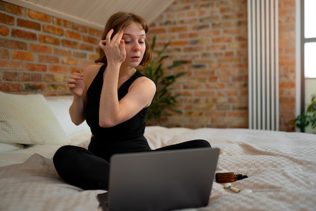 Foto mujer de tiro completo masajeando la cara en casa