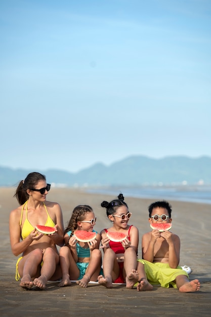 Foto mujer de tiro completo y niños con sandía.