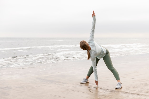 Foto mujer de tiro completo que se extiende en la playa