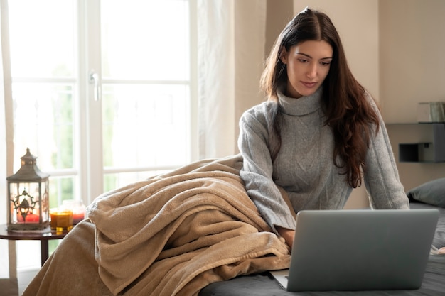 Mujer de tiro completo que trabaja en la computadora portátil