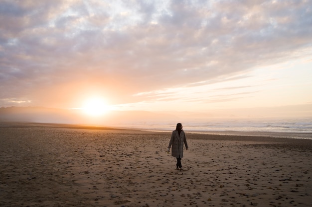 Foto mujer de tiro largo caminando en la playa
