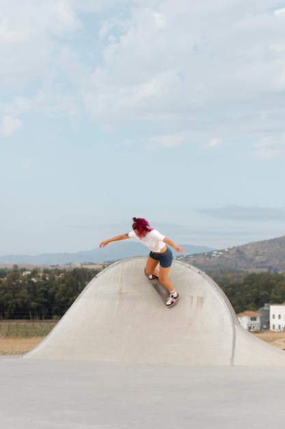 Foto mujer de tiro largo haciendo trucos con skate