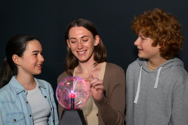 Foto mujer de tiro medio y niños interactuando con una bola de plasma