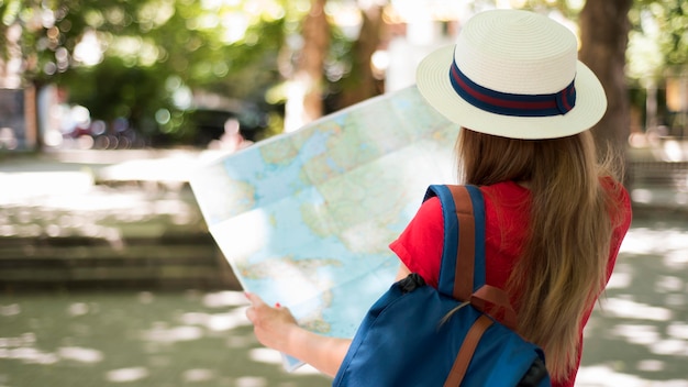 Foto mujer de tiro medio con sombrero y mapa exterior