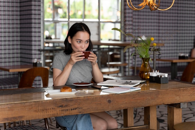 Mujer de tiro medio tomando café