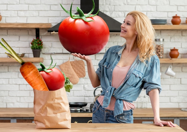 Foto mujer de tiro medio con tomate gigante.