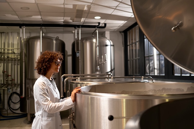 Foto mujer de tiro medio trabajando en fábrica de cerveza.