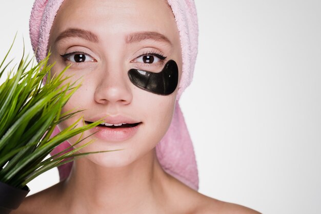 Una mujer con una toalla en la cabeza después de ducharse con parches debajo de los ojos.