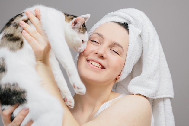 Mujer en una toalla sobre su cabeza con un gato en una luz