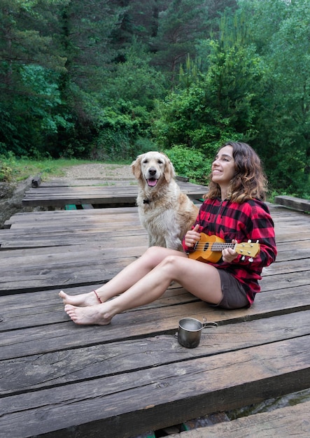 Mujer toca el ukelele con su perro